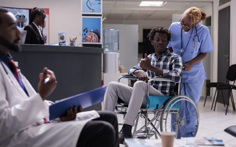 Person with chronic disability in waiting room at health center facility, wheelchair user waiting to attend checkup appointment. Man with physcal impairment doing consultation at medical clinic.